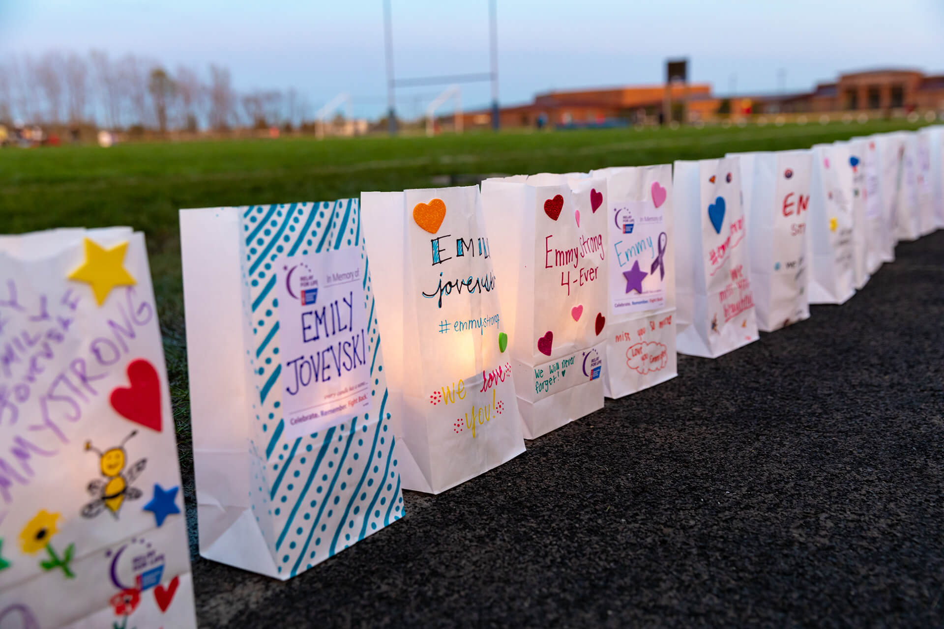 Line of paper bag lanterns along an athletic field.